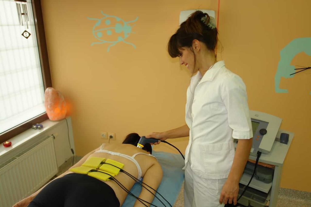 Nasmeh na obrazu fizioterapevta med terapijo z ultrazvokom